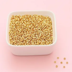 Macro shot of tiny gold-plated copper crimp beads in a ceramic bowl for DIY jewelry making