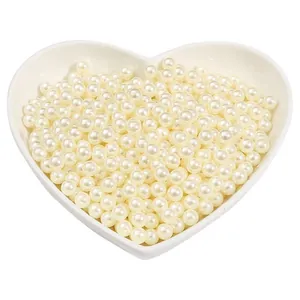 Perles rondes en ABS blanc crème présentées dans une coupelle en céramique en forme de cœur