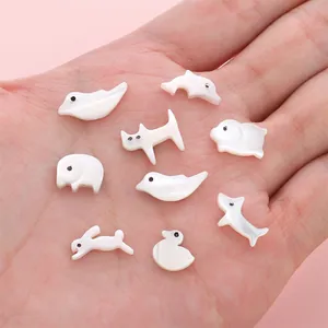 Hand holding assorted natural shell animal charms for DIY jewelry making and crafts
