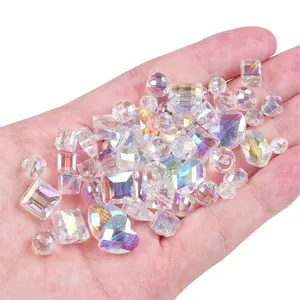 Assorted AB rainbow crystal glass heart and geometric beads held in hand for DIY jewelry