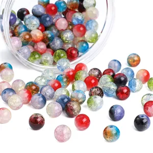 Bunte Crackle-Glasperlen fallen aus einem Glasgefäß für DIY-Schmuckherstellungsprojekte