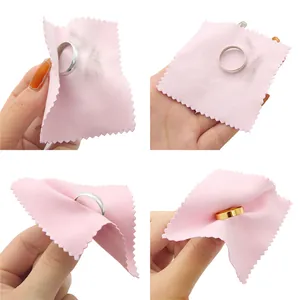 Pink jewelry cleaning cloth shown removing tarnish from gold and silver rings