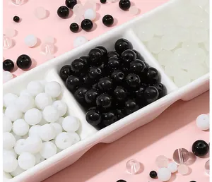 Gros plan de perles en verre noir, blanc et translucide pour bijoux DIY dans un plateau