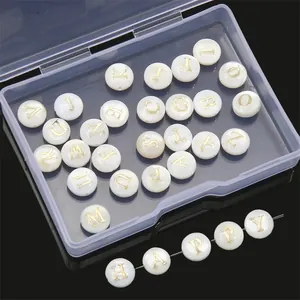 Macro view of shell-textured alphabet beads with gold letters and a storage box
