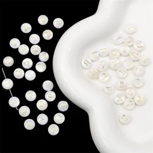 Detailed macro view of natural shell alphabet beads with gold-foil lettering for DIY jewelry