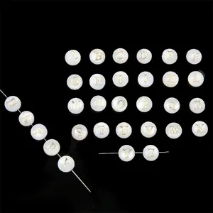 Detail view of natural shell beads with gold alphabets for DIY jewelry making