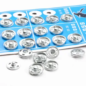 Polished silver metal press studs set on blue paper card for DIY sewing crafts