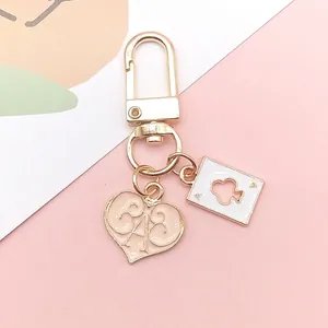 Detail of gold keychain with pink heart 643 and white ace of clubs card charms