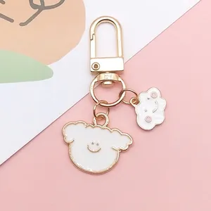 Detail of cute white enamel smiling cloud and puppy charms on a golden metal keychain