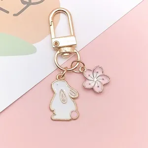 Close-up of a metal rabbit keychain with white enamel bunny and pink cherry blossom charms