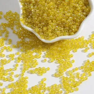 Perles de rocaille jaunes translucides pour bracelets DIY dans un plat en céramique