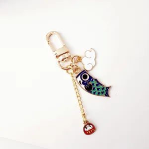 Golden Japanese Koi fish keychain with cloud and Daruma charm on white background