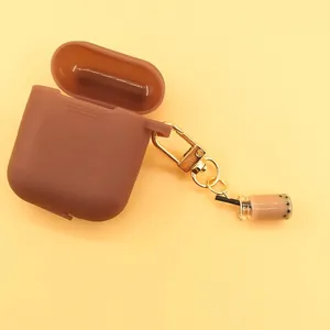 Detail of dark brown silicone earphone case with boba milk tea charm and gold clasp
