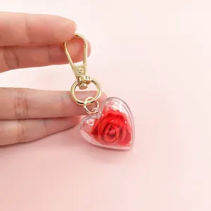 Detail of heart-shaped keychain with red rose inside and polished gold-tone metal hook