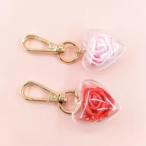 Detail of heart-shaped acrylic keychains with preserved roses and gold lobster clasps