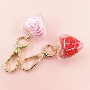 Detailed view of heart-shaped preserved rose keychains in pink and red with gold hooks