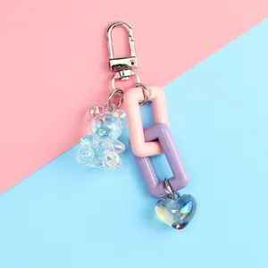 Cute iridescent bear and heart keychain with colorful chain links on pastel background