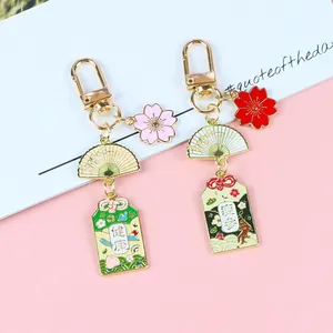 Détail du porte-clés japonais Omamori avec fleur de cerisier en émail et éventail