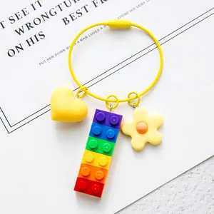 Detailed close-up of rainbow brick keychain with yellow heart and flower charms