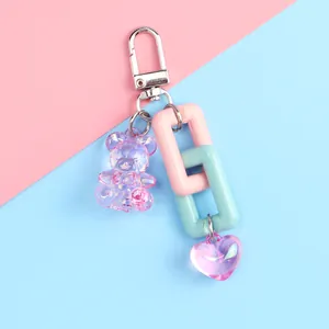 Detail of colorful resin bear keychain with plastic chains and heart charm on pastel background
