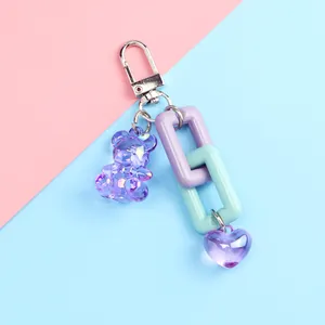 Detail of purple bear keychain with heart pendant and colorful links on pastel background