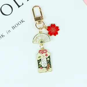 Détail du porte-clés japonais avec cerisier et Omamori sur un fond bleu minimaliste