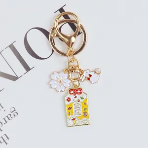 Close-up of Japanese style cherry blossom and lucky cat omamori keychain pendant