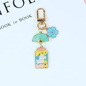 Détail de porte-clés japonais avec cerisier en émail éventail et porte-bonheur omamori