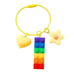 Rainbow building block keychain with heart and flower charms on a yellow wire loop