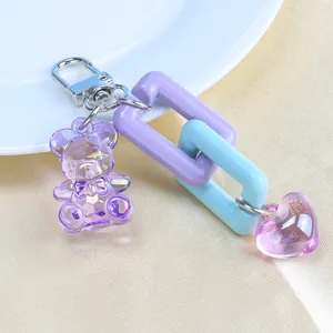 Close-up of cute purple resin bear and heart charms with matte blue chain links