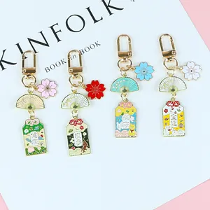 Porte-clés japonais omamori en métal avec fleurs de cerisier sur fond blanc minimaliste