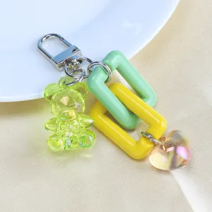 Detailed shot of cute bear keychain with neon rings and a heart pendant on silk background