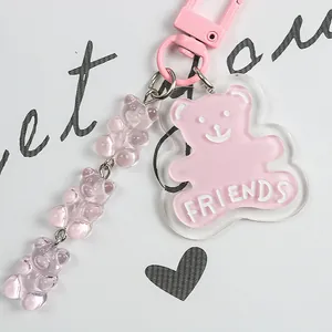Detail view of a pink acrylic bear keychain with a side chain of three gummy resin bears