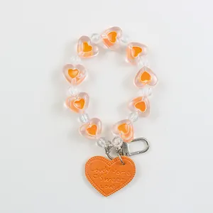 Macro detail of beaded heart keychain with orange leather heart and silver lobster clasp