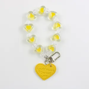 Detail of yellow heart-shaped beaded keychain with Lovely Home engraved leather charm