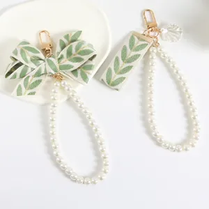 Long pearl wrist strap keychain with green leaf ribbon bow and golden metal clasp
