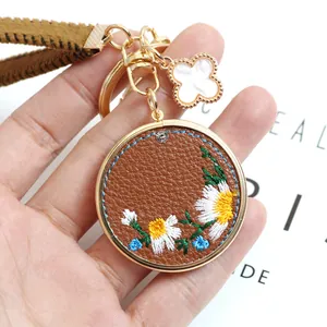 Handmade embroidered daisy PU leather keychain with brown woven strap and clover charm
