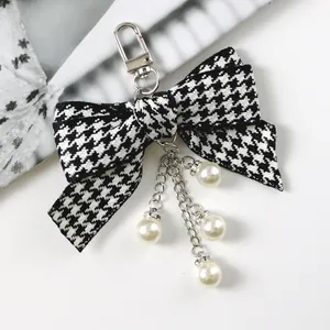 Close-up of houndstooth bow keychain with silver chains and sparkling faux pearls