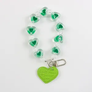 Detail of green beaded keychain with heart pendant and Lovely Home Sweet Love engraving