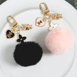 Detail of fluffy plush pompom keychains in black and pink with gold bear charms