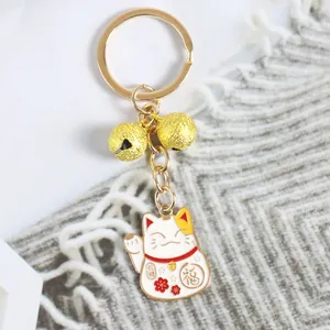 Gros plan d'un porte-clés Maneki Neko doré avec cloches et symbole de chance Fu