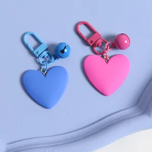 Detail of matte heart-shaped keychains in blue and pink with matching bells and lobster clasps