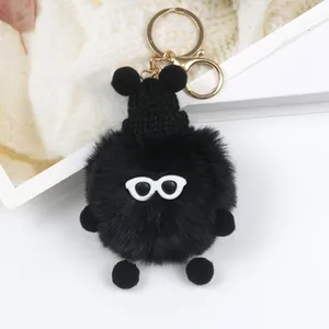 Dettaglio di un portachiavi in peluche nero con occhiali e mini berretto in maglia nera