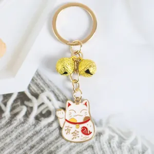 Détail d'un porte-clés chat porte-bonheur doré avec deux clochettes et gravure de poisson