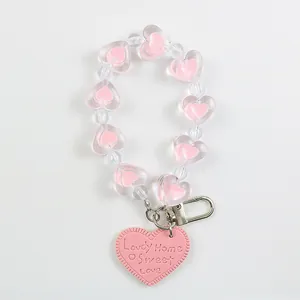 Detail of pink heart-shaped beads and faux leather tag on a keychain with metal clasp