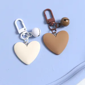 Detail of heart-shaped matte keychains with small bells in cream and coffee colors