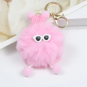 Dettaglio portachiavi in peluche rosa con cappello a maglia, occhiali e gancio dorato