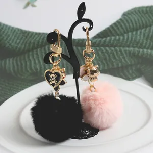 Detail of plush pompom keychains in black and pink with cute golden bear charms