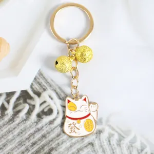 Détail du porte-clés chat porte-bonheur avec cloches dorées sur fond de pierre