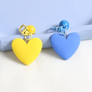 Close-up of matte heart-shaped charms in yellow and blue for bags or keychains